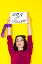 Young Latina woman with a purple scarf on her wrist holding a sign reading WOMEN LIFE FREEDOM. Royalty Free Stock Photo