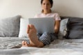 Young latina woman relax barefoot with laptop on comfy bed Royalty Free Stock Photo