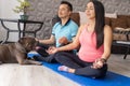 A young Latino couple whose wife is pregnant practices meditation in their living room with their bulldog next to them