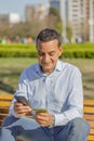 Young Latino man making a purchase with a credit card on his mobile phone in a public park Royalty Free Stock Photo