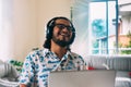 Young latino man smiling in front of his computer with headphones. Virtual meeting Royalty Free Stock Photo