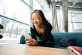 Young laughing asian female IT employee using smartphone on sofa at table Royalty Free Stock Photo