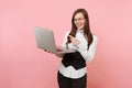 Young laughing attractive business woman holding using laptop pc computer pointing index finger isolated on pink Royalty Free Stock Photo