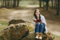 Young laughing beautiful woman in casual clothes sitting on stone studying reading book in city park or forest on green Royalty Free Stock Photo