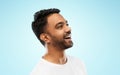 Young laughing indian man over gray background