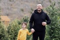 Young laughing man holds the hand of little cute girl. Smiling dad together with his sweet daughter in the park Royalty Free Stock Photo