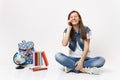 Young laughing overjoyed woman student with closed eyes talking on mobile phone, sitting near globe, backpack, school Royalty Free Stock Photo