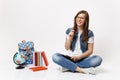 Young laughing pretty woman student in glasses holding pencil and notebook sitting near globe, backpack, school books Royalty Free Stock Photo