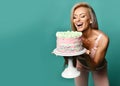 Young laughing sexy beautiful blonde fitness woman in bra and pants holding birthday holiday cake with cream Royalty Free Stock Photo