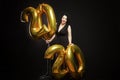 Young laughing woman with golden balls in the form of numbers of the New Year. Brunette with curly hair with red lipstick. Black Royalty Free Stock Photo