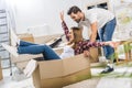 Young laughing woman sitting in a cardboard box while her boyfriend