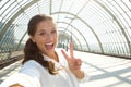 Young laughing woman taking selfie with peace sign