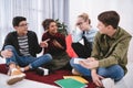 young laughting teenagers sitting on carpet studying and pointing Royalty Free Stock Photo