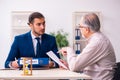 Young male lawyer and old man in testament and time management c Royalty Free Stock Photo