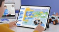 Young learner uses a tablet to program a small robot with colorful block coding interface Royalty Free Stock Photo