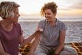 Young lesbian couple sitting on a beach blanket at dusk Royalty Free Stock Photo