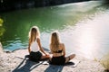 Young lesbian`s couple exercizing yoga at riverside in sunny day