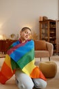 Young lgbt woman wrapped in rainbow flag feeling proud of her sexual orientation