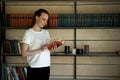 Young librarian searching books and taking one book from library bookshelf Royalty Free Stock Photo