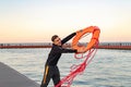 A young lifeguard on the shore throws an orange lifebuoy into the sea