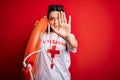 Young lifeguard woman wearing secury guard equipent holding rescue float over red background with open hand doing stop sign with
