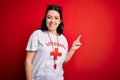 Young lifeguard woman wearing secury guard equipent over red background cheerful with a smile of face pointing with hand and