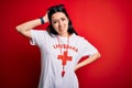 Young lifeguard woman wearing secury guard equipent over red background confuse and wonder about question