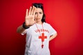 Young lifeguard woman wearing secury guard equipent over red background doing stop sing with palm of the hand