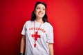 Young lifeguard woman wearing secury guard equipent over red background looking away to side with smile on face, natural