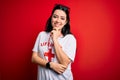 Young lifeguard woman wearing secury guard equipent over red background looking confident at the camera with smile with crossed