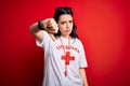 Young lifeguard woman wearing secury guard equipent over red background looking unhappy and angry showing rejection and negative