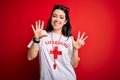 Young lifeguard woman wearing secury guard equipent over red background showing and pointing up with fingers number nine while
