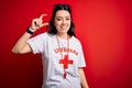 Young lifeguard woman wearing secury guard equipent over red background smiling and confident gesturing with hand doing small size