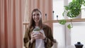 Young lifestyle blogger looks at the camera and makes video her home flowers