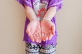 Young light-skinned Asian woman wearing a Balinese purple barong T-shirt showing both palms while standing