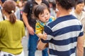 Young little Asian baby, in his father`s arm, look around at other people walking around them