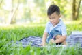 Young little asian boy reading and writing book in the park, asia kid homework and study in the summer, child relax with drawing Royalty Free Stock Photo
