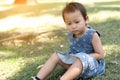 Young Little Asian kid sitting on grass outdoor park depressed and worry for distress, crying angry and afraid. Sad expression Royalty Free Stock Photo