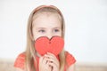 Young little blonde girl wearing in long sleeveless dress holding red cardboard heart Royalty Free Stock Photo