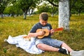 Young little boy guitarist outdoor. Boy on city park summer meadow enjoying day playing guitar Royalty Free Stock Photo