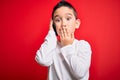 Young little boy kid talking on smartphone mobile over red isolated background cover mouth with hand shocked with shame for Royalty Free Stock Photo