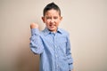 Young little boy kid wearing elegant shirt standing over isolated background angry and mad raising fist frustrated and furious Royalty Free Stock Photo