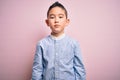 Young little boy kid wearing elegant shirt standing over pink isolated background with serious expression on face Royalty Free Stock Photo