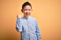 Young little boy kid wearing elegant shirt standing over yellow isolated background angry and mad raising fist frustrated and Royalty Free Stock Photo
