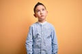 Young little boy kid wearing elegant shirt standing over yellow isolated background Relaxed with serious expression on face Royalty Free Stock Photo