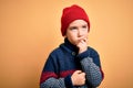 Young little boy kid wearing wool cap and winter sweater over yellow isolated background with hand on chin thinking about Royalty Free Stock Photo