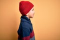 Young little boy kid wearing wool cap and winter sweater over yellow isolated background looking to side, relax profile pose with Royalty Free Stock Photo