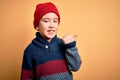 Young little boy kid wearing wool cap and winter sweater over yellow isolated background smiling with happy face looking and Royalty Free Stock Photo