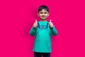 Young little boy thumbs up with both hands on plain color background