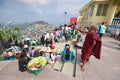 Young little Buddhist monk pointing somewhere afar while pilgrims passing by & vendors selling snacks along the stairs Royalty Free Stock Photo